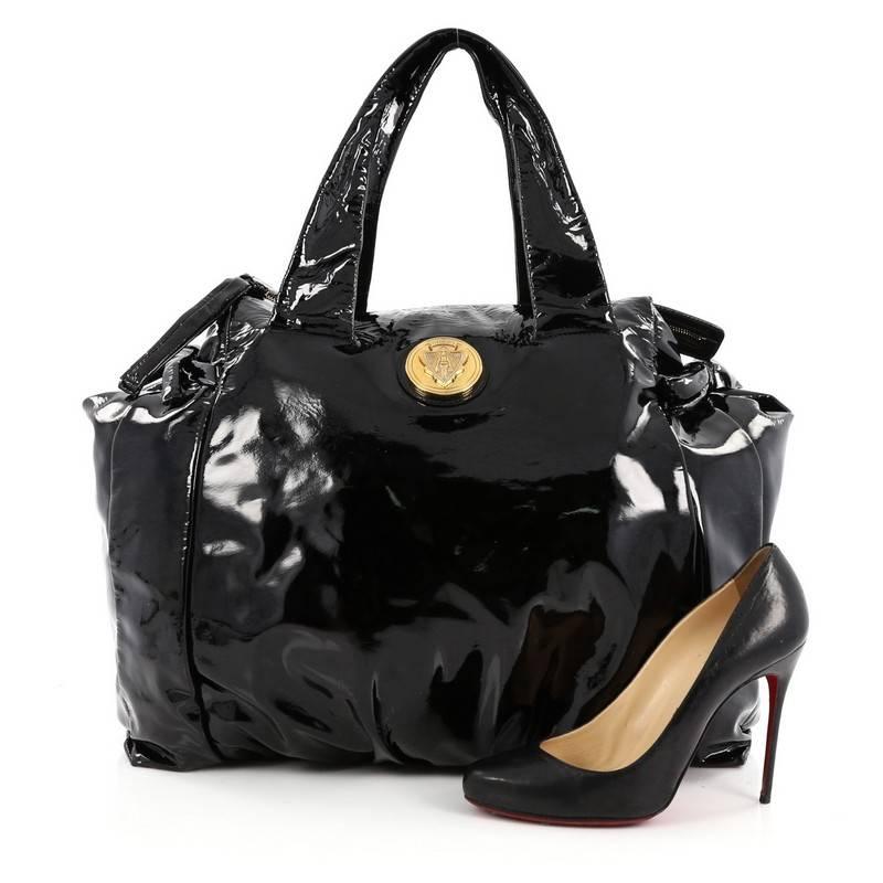 This authentic Gucci Hysteria Tote Patent Large is a lovely addition for any Gucci lover's closet. Constructed from black patent leather, this oversized tote features bow ties on both sides for expansion, pleated details, gold Gucci crest at its