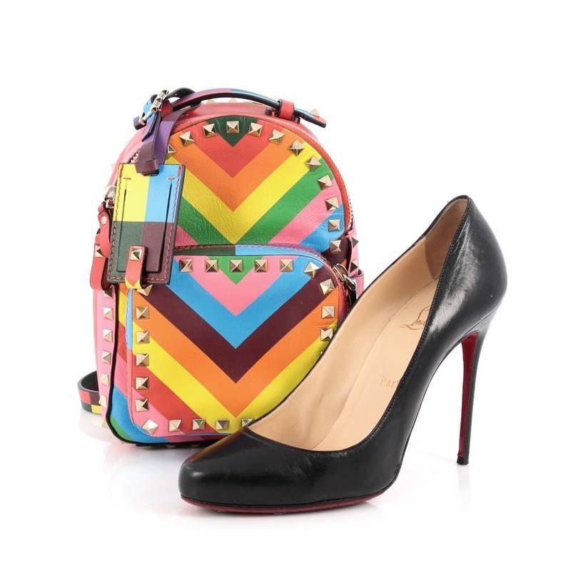 This authentic Valentino 1973 Rockstud Backpack Striped Leather Mini mixes bold and chic style perfect for on the moments. Crafted from rainbow multicolor chevron striped leather, this compact backpack features Valentino's signature pyramid rockstud