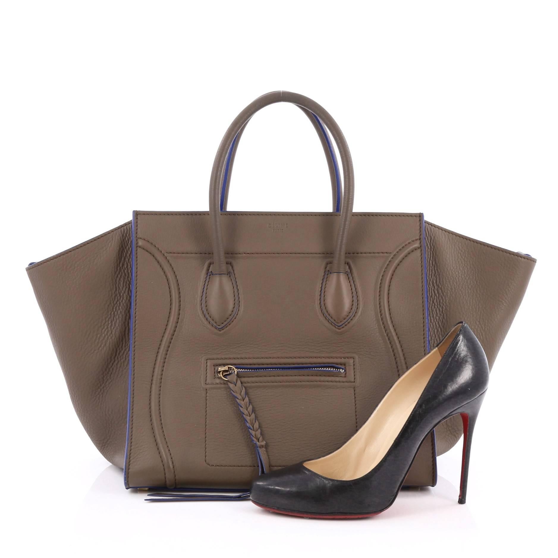This authentic Celine Phantom Handbag Grainy Leather Medium is one of the most sought-after bags beloved by fashionistas. Crafted from olive green grainy leather with blue piping, this minimalist tote features dual-rolled handles, an exterior front