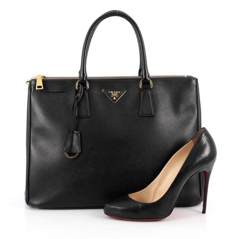 This authentic Prada Double Zip Lux Tote Saffiano Leather Large is the perfect bag to complete any outfit. Crafted from black saffiano leather, this boxy tote features side snap buttons, raised Prada logo, dual-rolled leather handles and gold-tone
