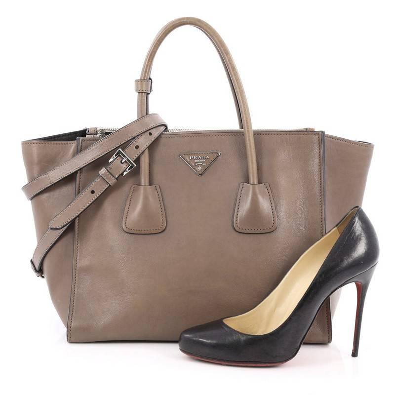 This authentic Prada Twin Pocket Tote Glace Calf Medium showcases a sophisticated silhouette balancing modern luxury and style perfect for the on-the-go woman. Crafted from glossy glace calf leather in argilla brown, this boxy tote features tall