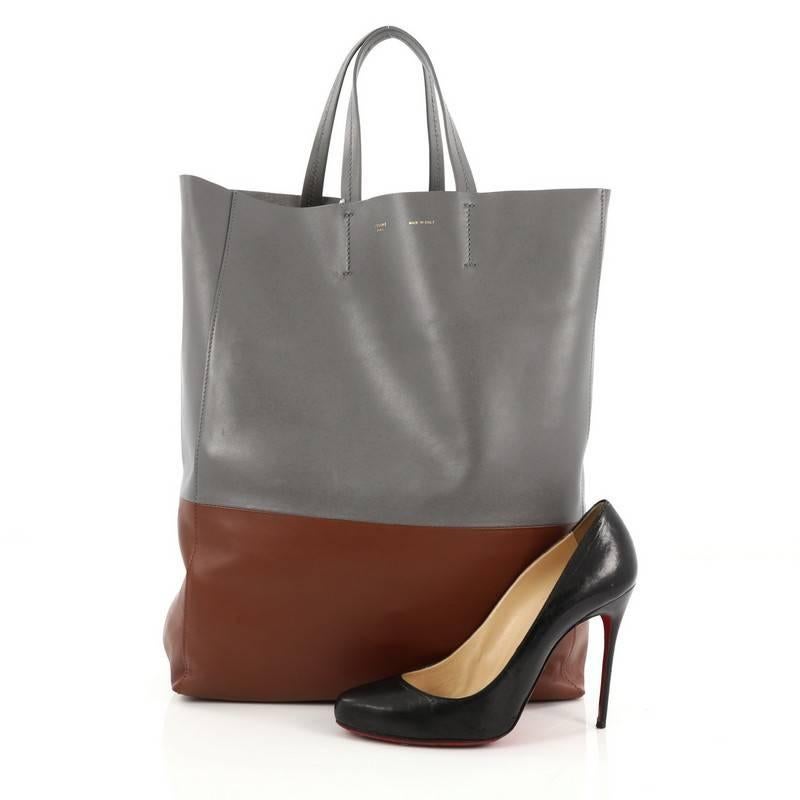 This authentic Celine Vertical Bi-Cabas Tote Leather Large is a perfect everyday accessory for the woman on-the-go. Crafted in minimalistic bi-color grey and brown leather, this no-fuss tall tote features slim top handles and gold-tone hardware