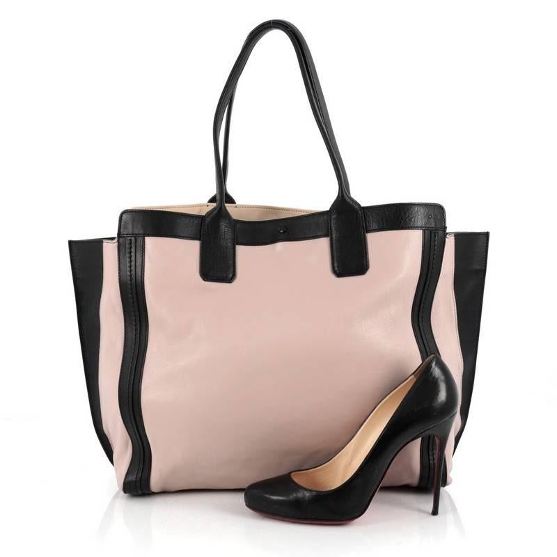 This authentic Chloe Alison East West Tote Leather Large is perfect for an everyday bag. Constructed from light pink and black leather, this simple, functional tote features dual-rolled handles with winged sides and gold-tone hardware accents. Its