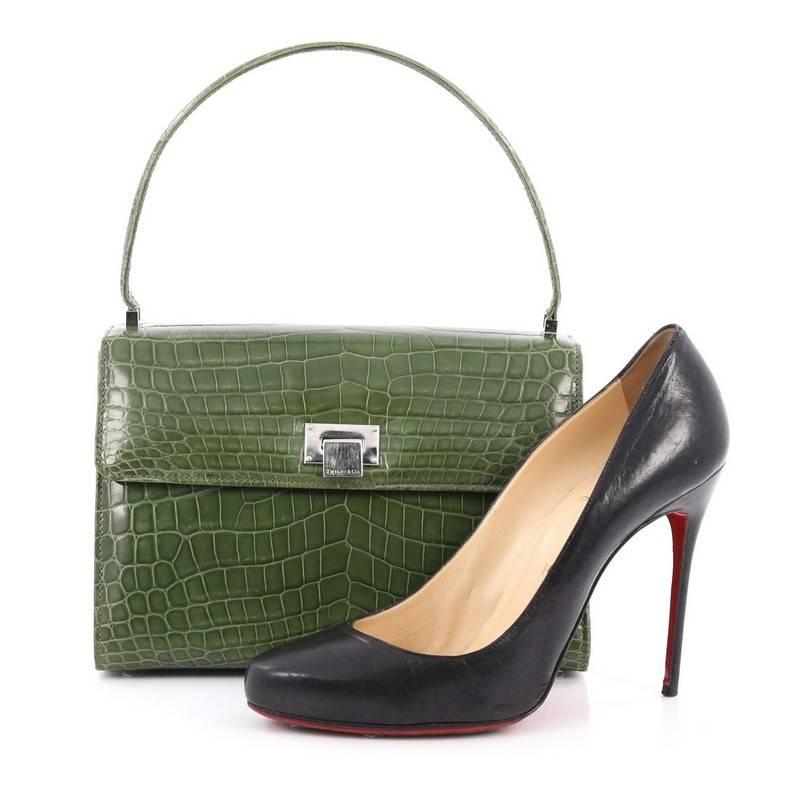 This authentic Tiffany & Co. Maddie Lunchbox Bag Crocodile Small is a chic and sophisticated bag perfect for everyday look. Crafted in genuine green crocodile skin, this bag features single loop top handle, frontal flap, protective base studs