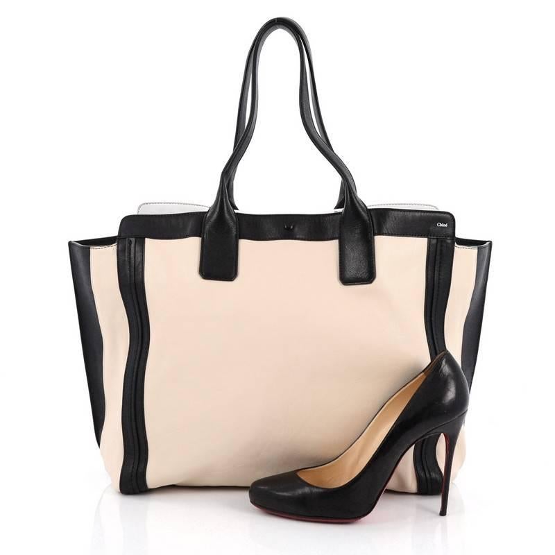 This authentic Chloe Alison East West Tote Leather Medium is a perfect everyday bag. Crafted from light beige leather with black leather trims, this tote features a winged silhouette, dual tall flat handles, subtle stamped Chloe name, and gold-tone