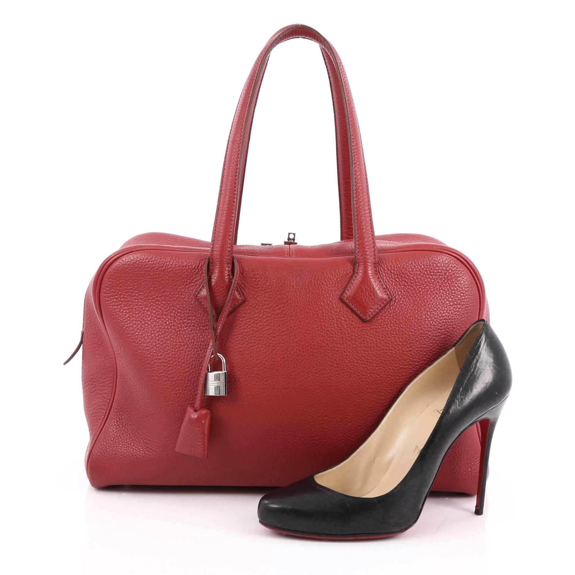 This authentic Hermes Victoria II Handbag Clemence 35 is the perfect understated accessory for all seasons. Created in beautiful rubis red leather, this all-around understated functional tote features tall dual leather handles, protective base