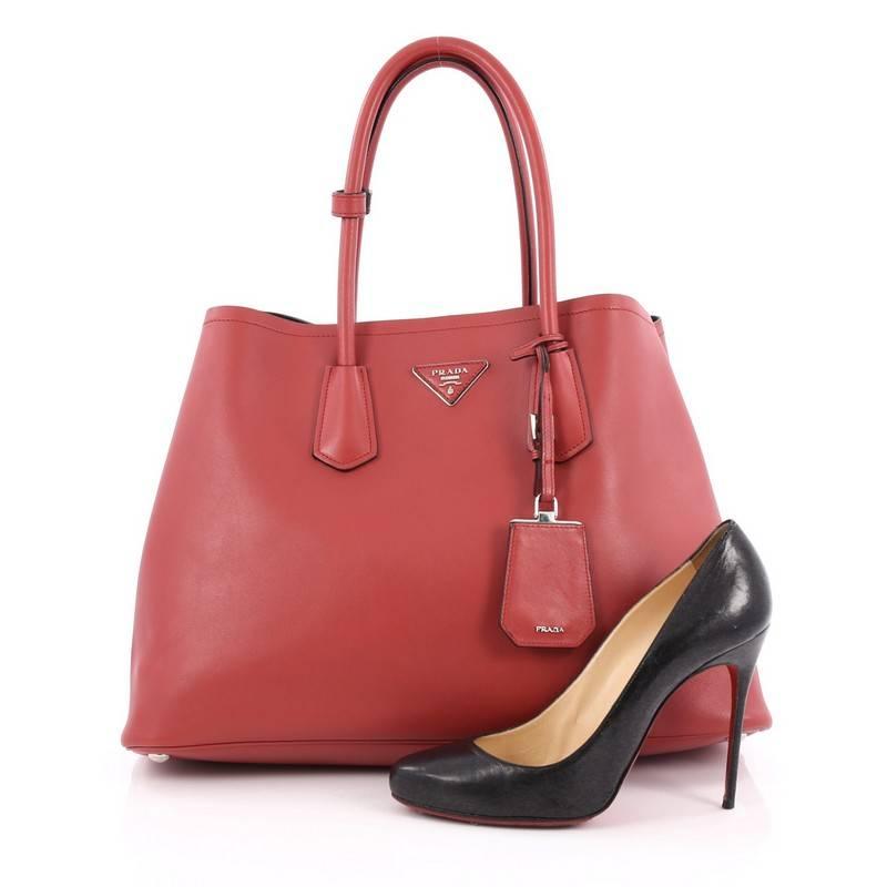 This authentic Prada Cuir Double Tote City Calfskin Medium is a mark of Prada's fine craftsmanship that is elegant in its simplicity and structure. Crafted from red leather, this tote features dual-rolled handles, side snap buttons, protective base