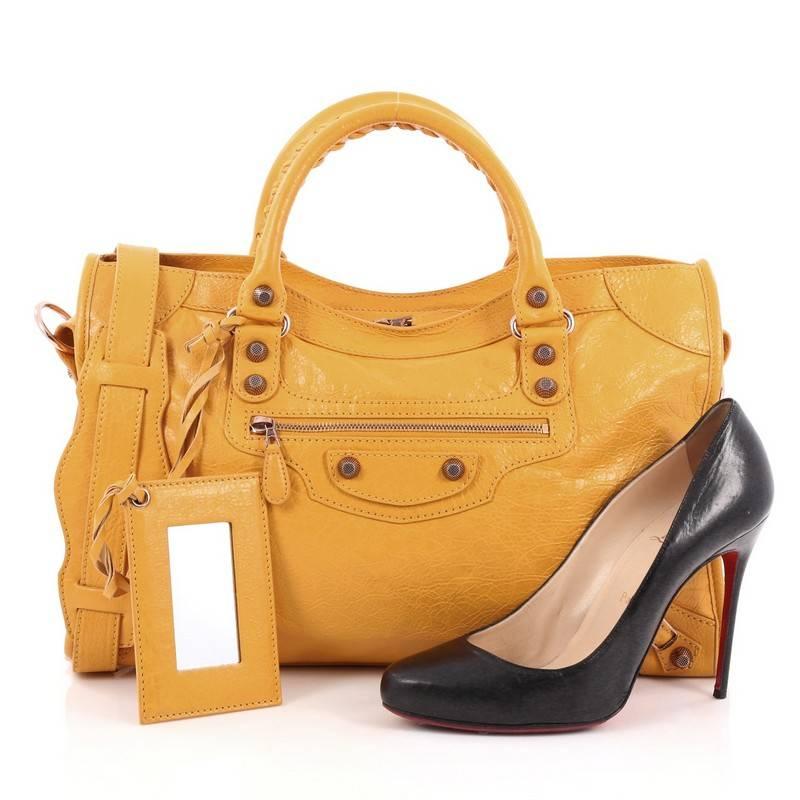 This authentic Balenciaga City Giant Studs Handbag Leather Medium is for the on-the-go fashionista. Constructed from mangue yellow leather, this popular bag features dual braided woven tall handles, exterior front zip pocket, iconic Balenciaga giant