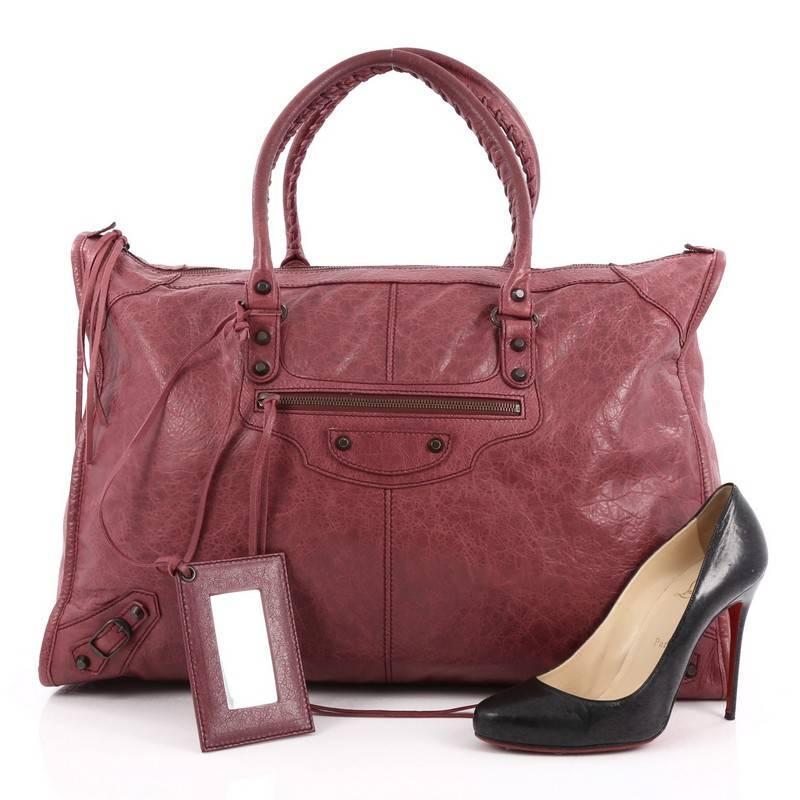This authentic Balenciaga Weekender Classic Studs Handbag Leather is a stylish and fun accessory made for light travels and weekend getaways. Constructed from maroon leather, this oversized, lightweight carryall features braided woven handle straps,