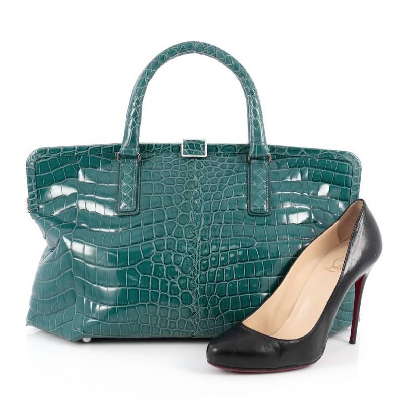 This authentic Bottega Veneta Frame Tote Crocodile Medium is a timeless, elegant tote with a structured, chic silhouette. Crafted in genuine teal crocodile skin this tote features short dual-rolled top handles, framed top, protective base studs and