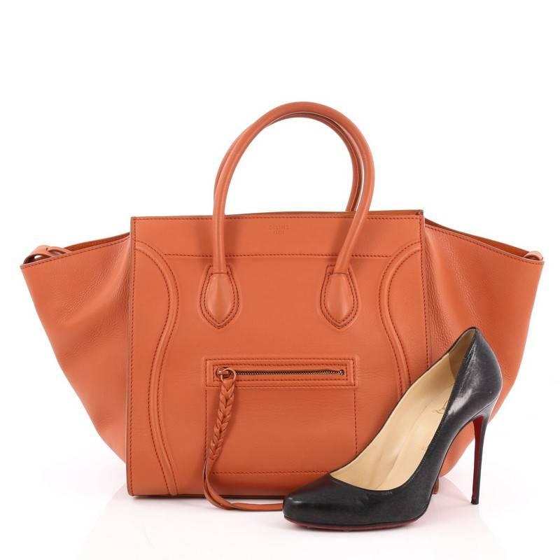 This authentic Celine Phantom Handbag Grainy Leather Large is one of the most sought-after bags beloved by fashionistas. Crafted from orange grainy leather, this minimalist tote features dual-rolled handles, an exterior front pocket with braided