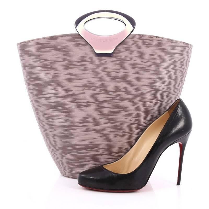 This authentic Louis Vuitton Noctambule Handbag Epi Leather is a sleek and stylish accessory to complement any sophisticated outfit. Crafted from dusty lavender epi leather, this structured top handle tote features circular resin handles, reinforced