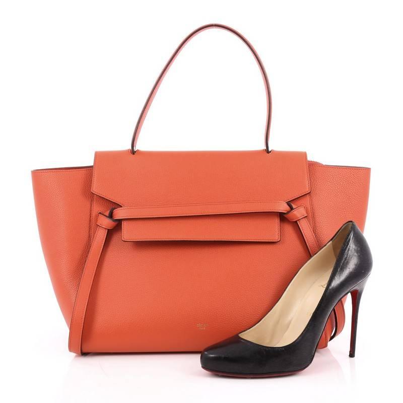 This authentic Celine Belt Bag Grainy Leather Small is sure to make a statement. Crafted from orange grainy leather, this bold and beautiful bag features expanded wings, looped single top handle, top flap slide closure, knotted ties, zipper pocket
