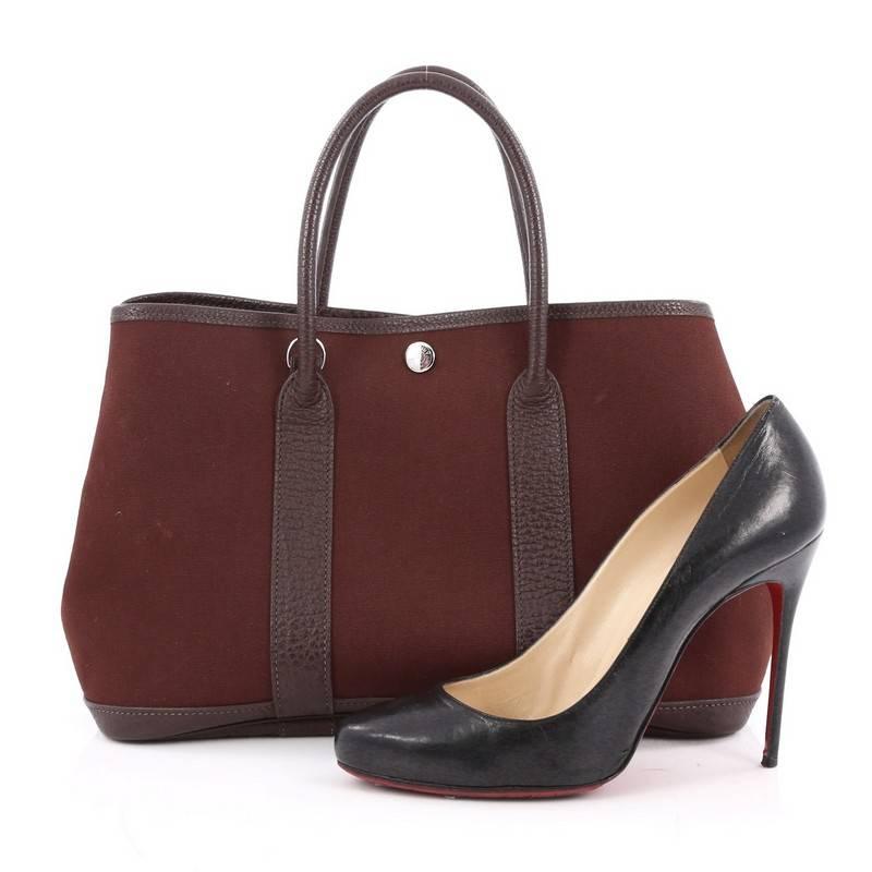 This authentic Hermes Garden Party Tote Toile and Leather 30 is an elegant and simple tote made for all seasons. Crafted from marron fonce brown fabric with brown leather trims, this chic everyday tote features dual-rolled leather top handles,