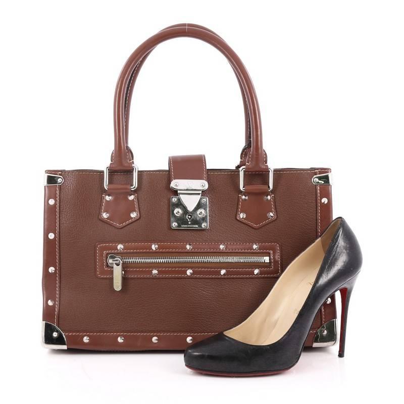 This authentic Louis Vuitton Suhali Le Fabuleux Handbag Leather showcases a structured yet eye-catching elegant design. Crafted from sturdy, sienne brown suhali leather, this trunks-inspired tote features dual-rolled handles, exterior front zip