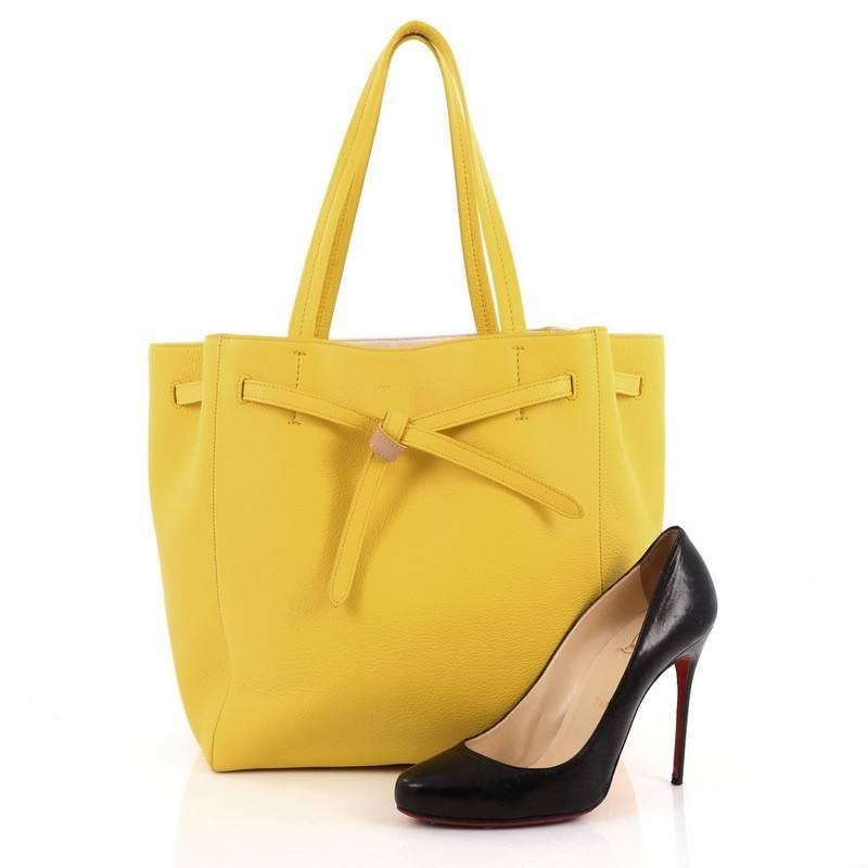 This authentic Celine Phantom Tie Cabas Tote Leather Small is a fashionista's go-to stylish essential. Crafted from yellow leather, this minimalist, city tote features dual flat tall handles, stamped Celine logo, and gold-tone hardware accents. Its