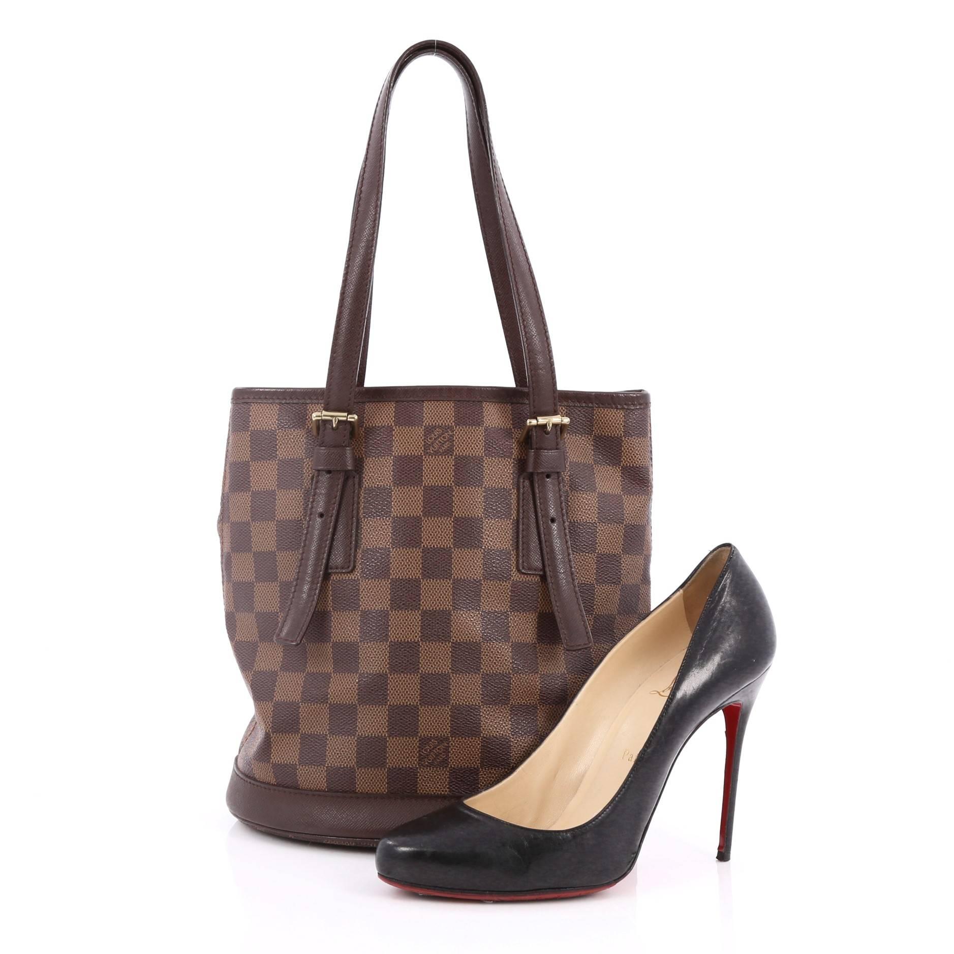This authentic Louis Vuitton Marais Bucket Bag Damier is easy to transform from season to season. Crafted in damier ebene canvas, this simple and chic bucket bag features adjustable shoulder straps, protective base studs and gold-tone hardware
