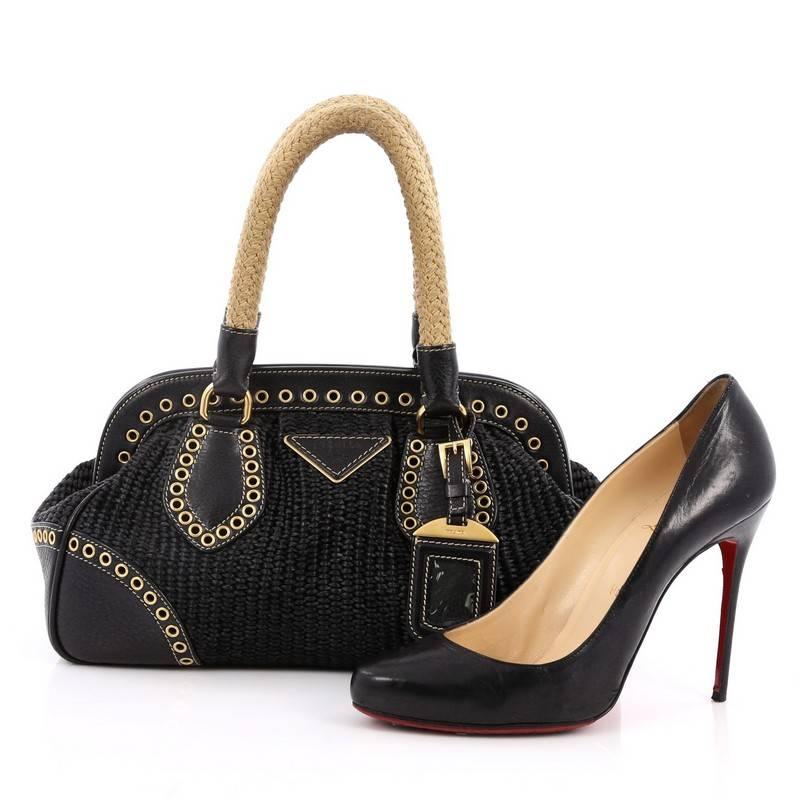 This authentic Prada Frame Satchel Woven Raffia Small is an edgy , sophisticated carry-all bag with a modern twist. Crafted from black woven raffia with black leather trims, this luxurious bag features dual-rolled woven handles, grommet