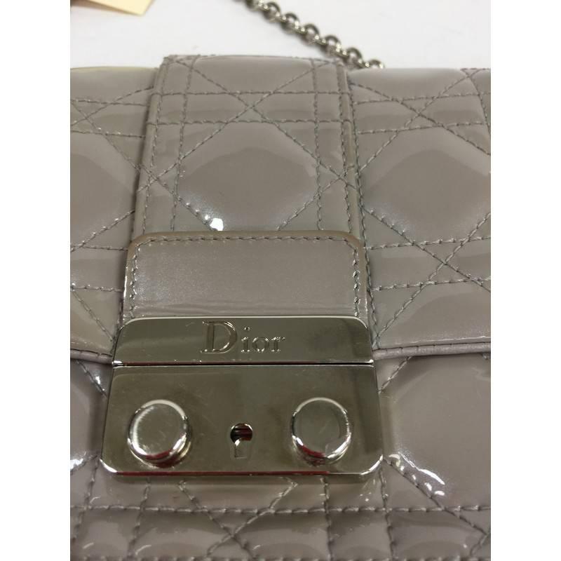 This authentic Christian Dior New Lock Pouch Cannage Quilt Patent Mini is an elegant, classic accessory made for every fashionista. Crafted from grey patent leather in Dior's famous cannage quilting, this petite crossbody features a detachable