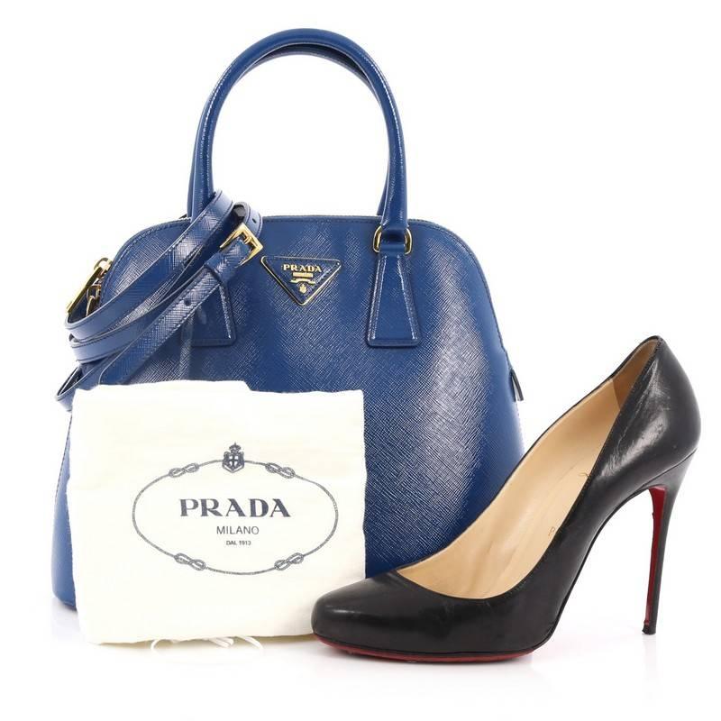 This authentic Prada Zip Around Convertible Dome Satchel Vernice Saffiano Leather North South is elegant in its simplicity and structure. Crafted in blue saffiano leather, this sleek dome-shaped satchel features dual-rolled handles, removable