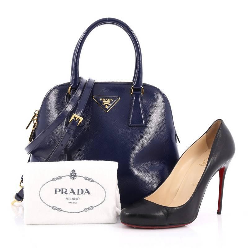 This authentic Prada Zip Around Convertible Dome Satchel Vernice Saffiano Leather North South is the perfect companion for an everyday stroll. Crafted from dark blue vernice saffiano leather, this chic dome-shaped bag features dual-rolled handles,