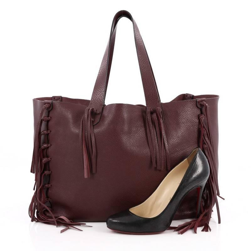 This authentic Valentino C-Rockee Fringe Tote Leather Large presented in its Spring/Summer 2014 Collection mixes the brand's penchant for bohemian style with modern, chic flair made for any fashionista. Crafted from burgundy pebbled leather, this
