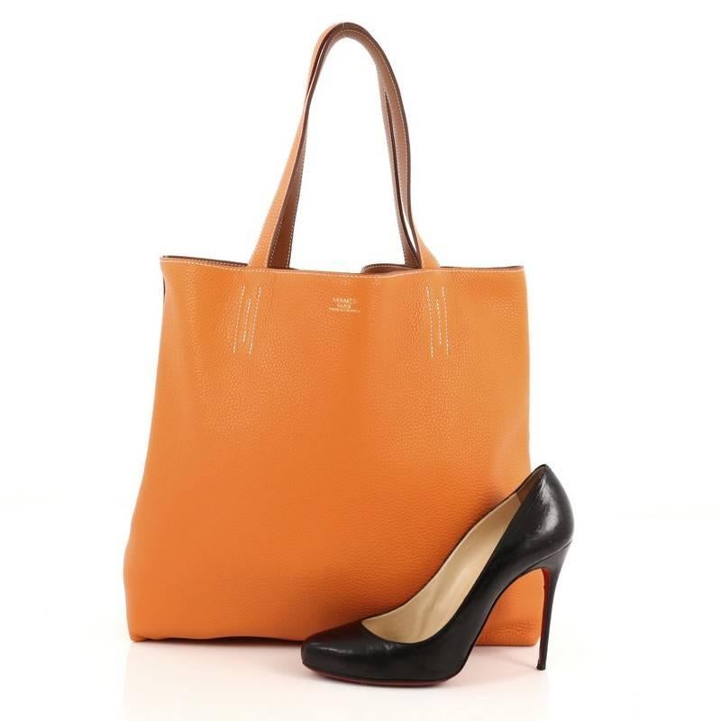 This authentic Hermes Double Sens Tote Clemence 36 combines a simple and functional style from Hermes perfect for everyday use. Crafted from soft luxurious reversible veau taurillon clemence leather in orange and gold, this versatile tote features
