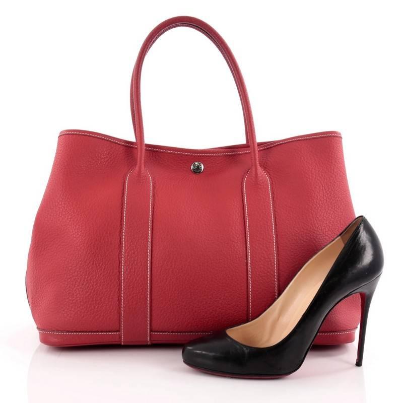 This authentic Hermes Garden Party Tote Leather 36 is an elegant and simple tote bag made for all seasons. Crafted from sturdy sanguine red leather, this chic everyday tote features dual-rolled top handles, palladium button closure, side snap
