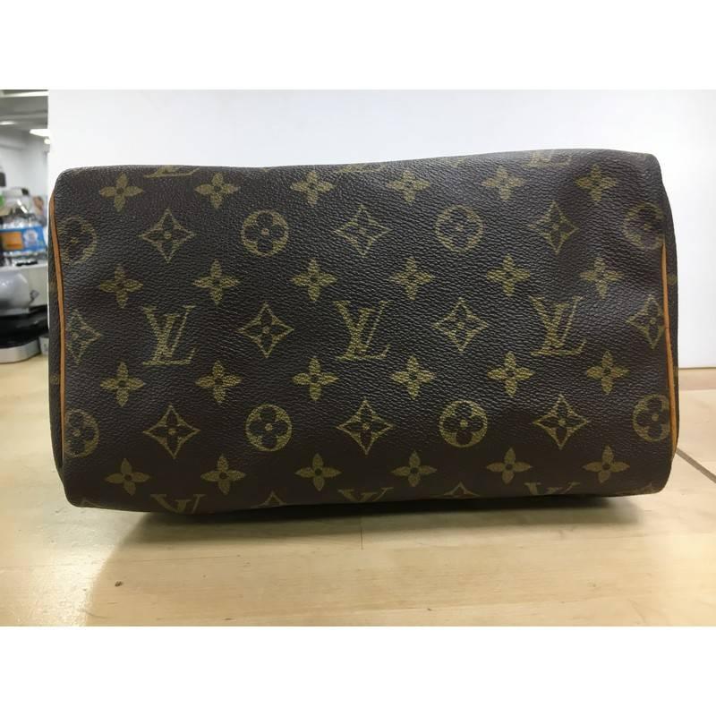 This authentic Louis Vuitton Speedy Handbag Monogram Canvas 25 is spacious and light, making it ideal to use everyday. Constructed in Louis Vuitton's classic brown monogram coated canvas, this iconic Speedy features dual-rolled leather handle,