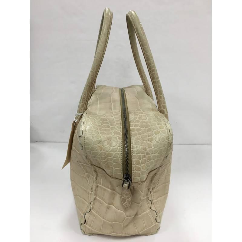 This authentic Alaia Puzzle Zip Tote Crocodile Embossed Leather Medium personifies the brand's quintessential sleek yet chic everyday style. Designed in beige crocodile embossed leather, this tote features, dual-rolled handles, interlocking leather