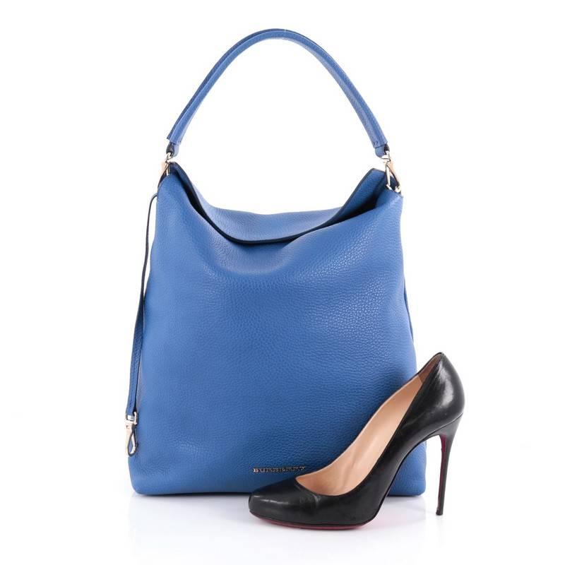 This authentic Burberry Cale Hobo Grainy Leather Medium is a simple accessory that is elegant yet understated made for the everyday woman. Crafted from blue grainy leather, this simple hobo features a flat leather top handle, raised Burberry