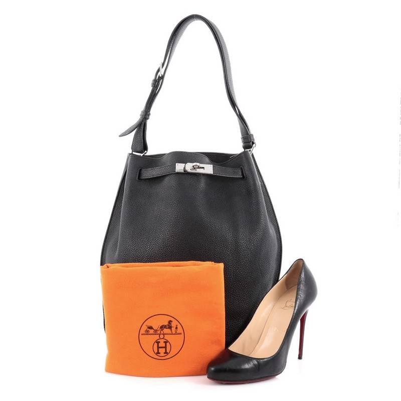 This authentic Hermes So Kelly Handbag Togo 26, first released in 2008, is an updated and modern reinterpretation of the Kelly Sport taking its distinct look to Hermes' classic kelly design. Crafted in black leather, this luxurious hobo-inspired bag