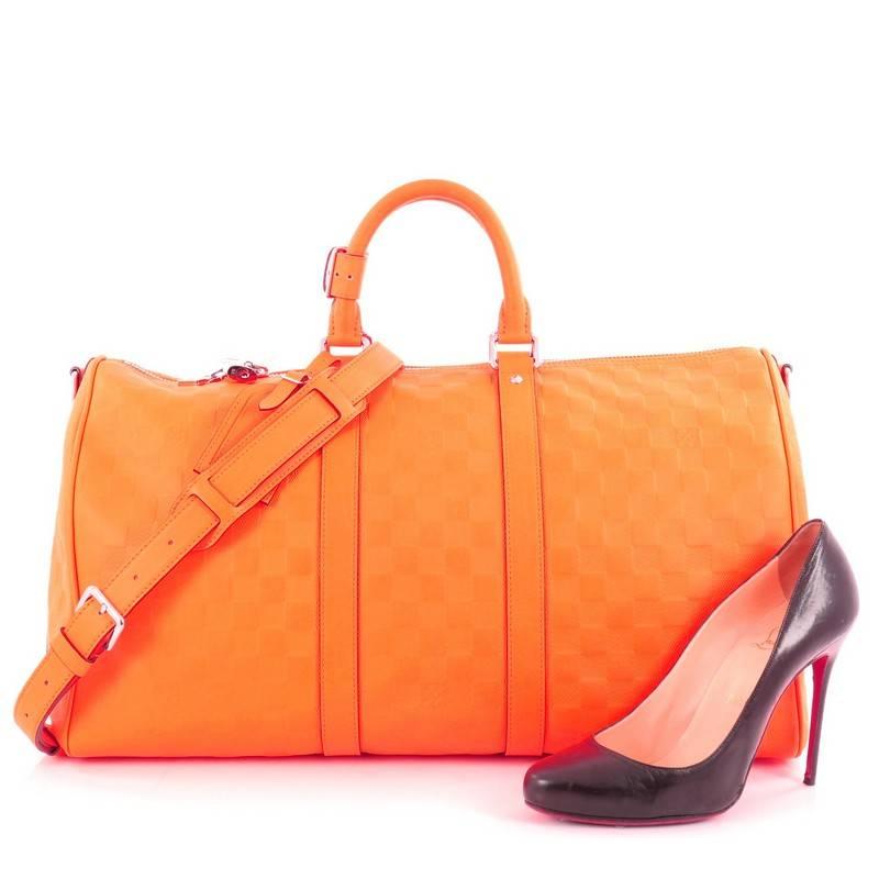 This authentic Louis Vuitton Keepall Bandouliere Bag Damier Infini Leather 45 is the perfect purchase for a weekend trip, and can be effortlessly paired with any outfit from casual to formal. Crafted from Louis Vuitton damier infini neon orange