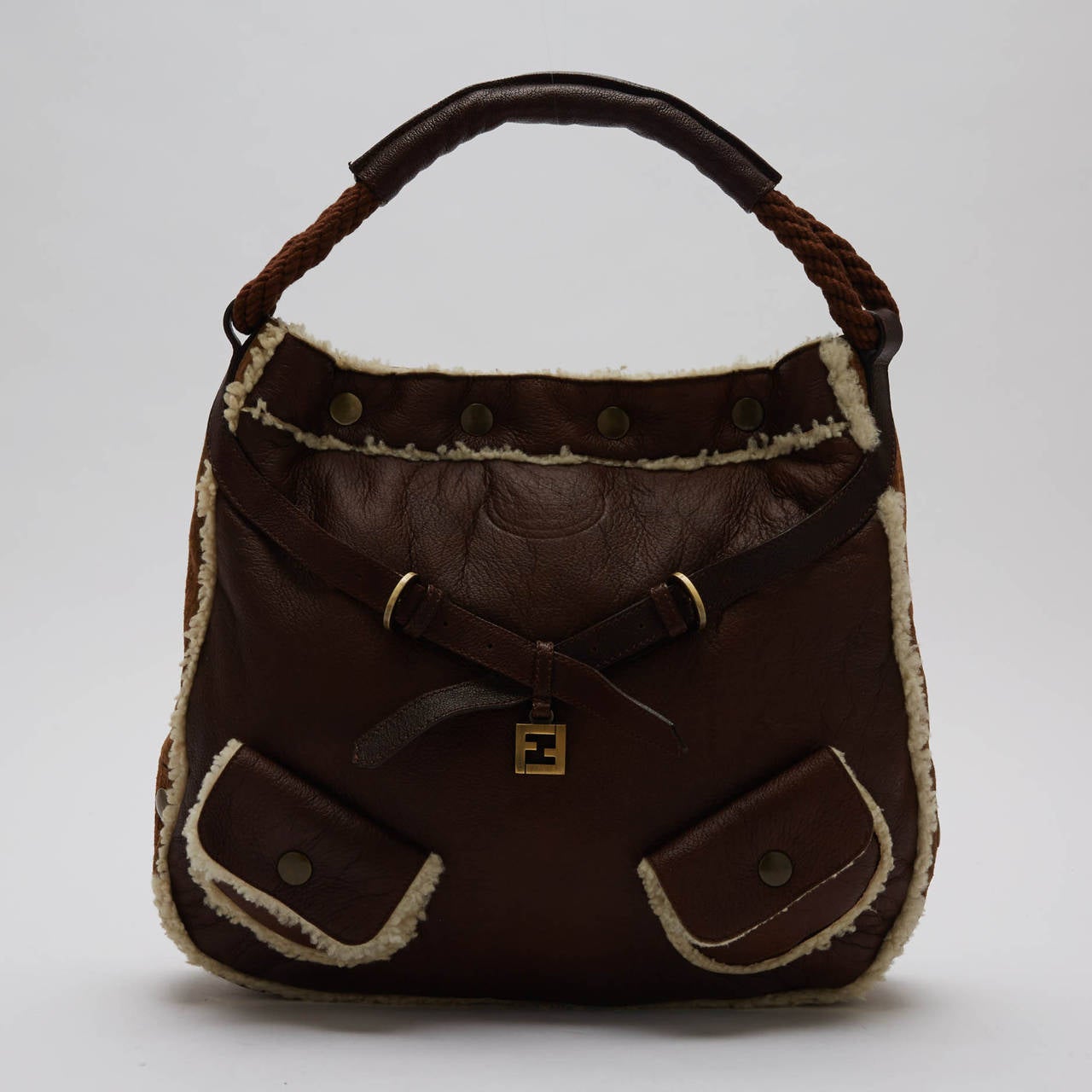 This unconventional Fendi Hobo Tote is made with soft shearling and suede at the sides. It features a brown smooth rope handle wrapped in soft leather, and is finished with brushed gold hardware. The blend of materials makes this an essential