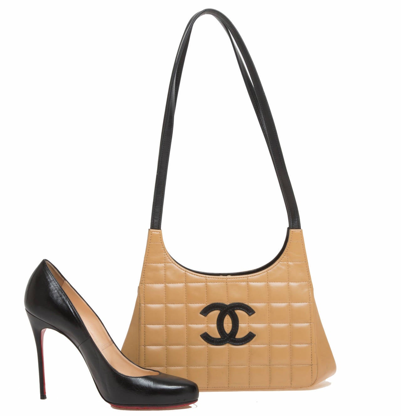 This chic Chanel Chocolate Bar Leather Shoulder Bag has an intricate design and certainly makes a statement. Constructed with soft beige leather, the bag dons square quilts and the signature double C logo in black leather on front. The smooth black
