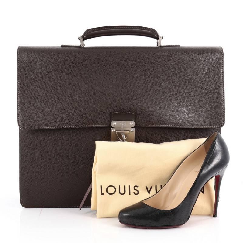 This authentic Louis Vuitton Robusto 2 Briefcase Taiga Leather combines style and functionality ideal for work. Crafted from brown taiga leather, this structured briefcase features a looped top handle, a push-lock flap closure, subtle LV stamped