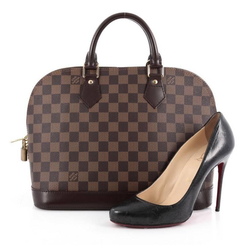 This authentic Louis Vuitton Vintage Alma Handbag Damier PM is an elegant spin on a classic style that is perfect for all seasons. Crafted from Louis Vuitton's damier ebene coated canvas, this dome-shaped satchel features dual-rolled handles, dark