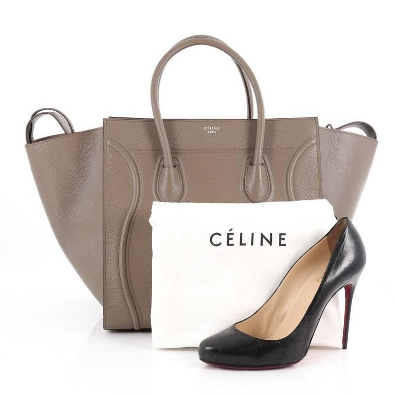 This authentic Celine Phantom Handbag Textured Leather Medium is one of the most sought-after bags beloved by fashionistas. Crafted from taupe textured leather, this minimalist tote features dual-rolled handles, an exterior front pocket, protective