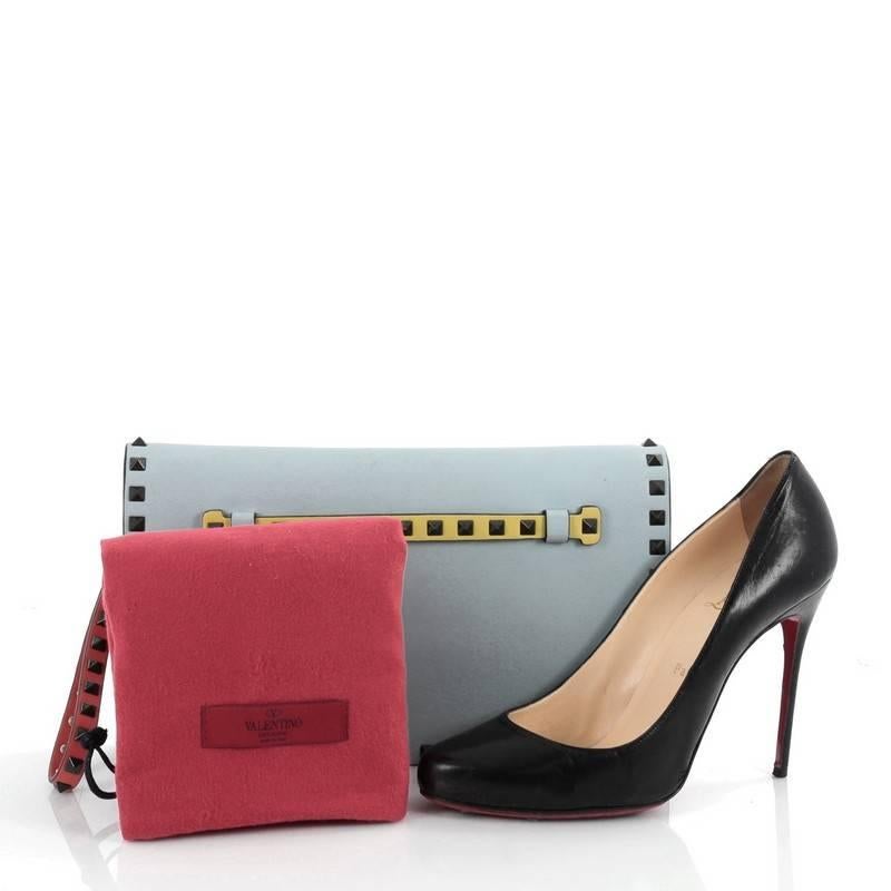 This authentic Valentino Rockstud Flap Clutch Leather is a chic yet functional accessory perfect for on-the-go moments. Crafted from light blue leather, this trendy clutch features a leather hand sling, back studded hand strap, polished gunmetal