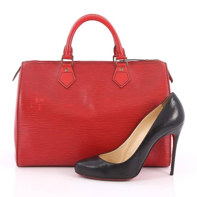 This authentic Louis Vuitton Speedy Handbag Epi Leather 30 is a timeless favorite of many. Crafted in red epi leather, this bag features dual-rolled handles, subtle stamped LV logo, exterior side slip pocket and aged gold-tone hardware accents. Its