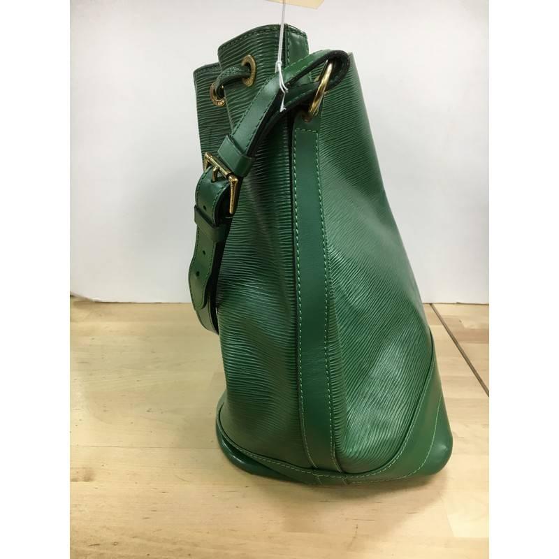 This authentic Louis Vuitton Noe Handbag Epi Leather Large is a chic and iconic bucket bag made for the modern fashionista. Crafted from borneo green epi leather, this bucket bag features adjustable shoulder straps, subtle LV logo, leather