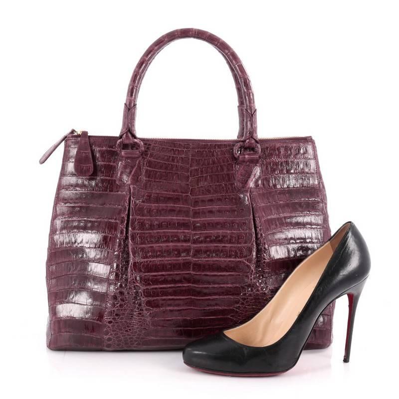 This authentic Nancy Gonzalez Double Zip Convertible Tote Crocodile Large is the perfect combination of luxurious style and a polished aesthetic with a fun twist. Crafted from plum genuine crocodile skin, this tote features dual-rolled handles,