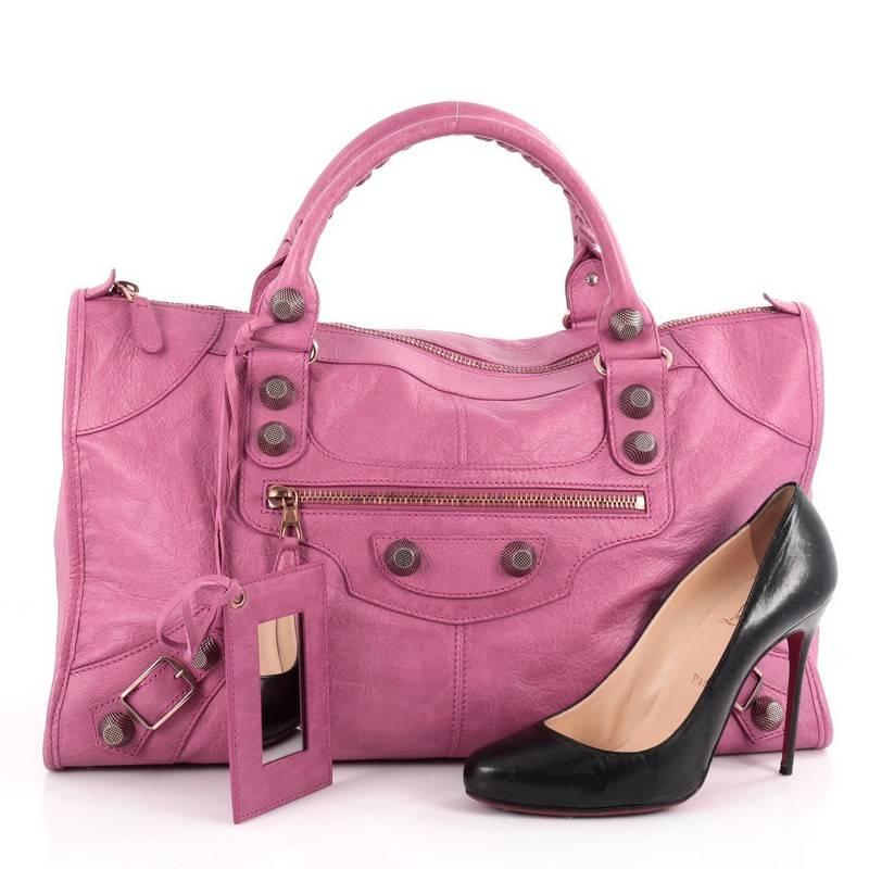 This authentic Balenciaga Work Giant Studs Handbag Leather is for the on-the-go fashionista. Constructed in cyclamen fuchsia leather, this popular bag features braided woven handles, front zipped pocket, buckle details, iconic Balenciaga giant rose