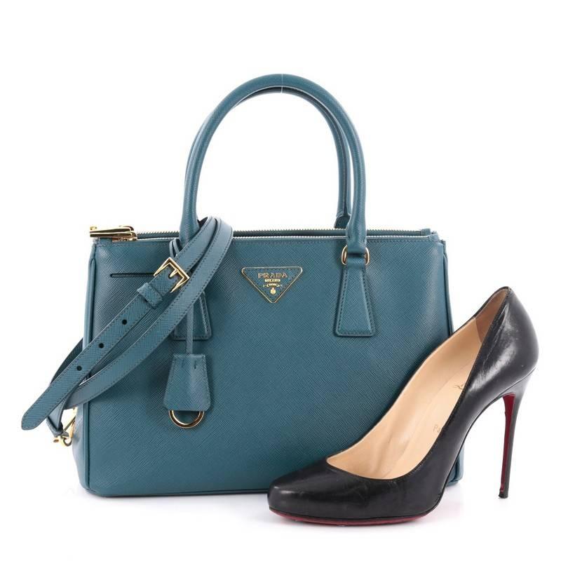This authentic Prada Double Zip Lux Tote Saffiano Leather Small is the perfect bag to complete any outfit. Crafted from teal saffiano leather, this boxy tote features side snap buttons, raised Prada logo, dual-rolled leather handles and gold-tone