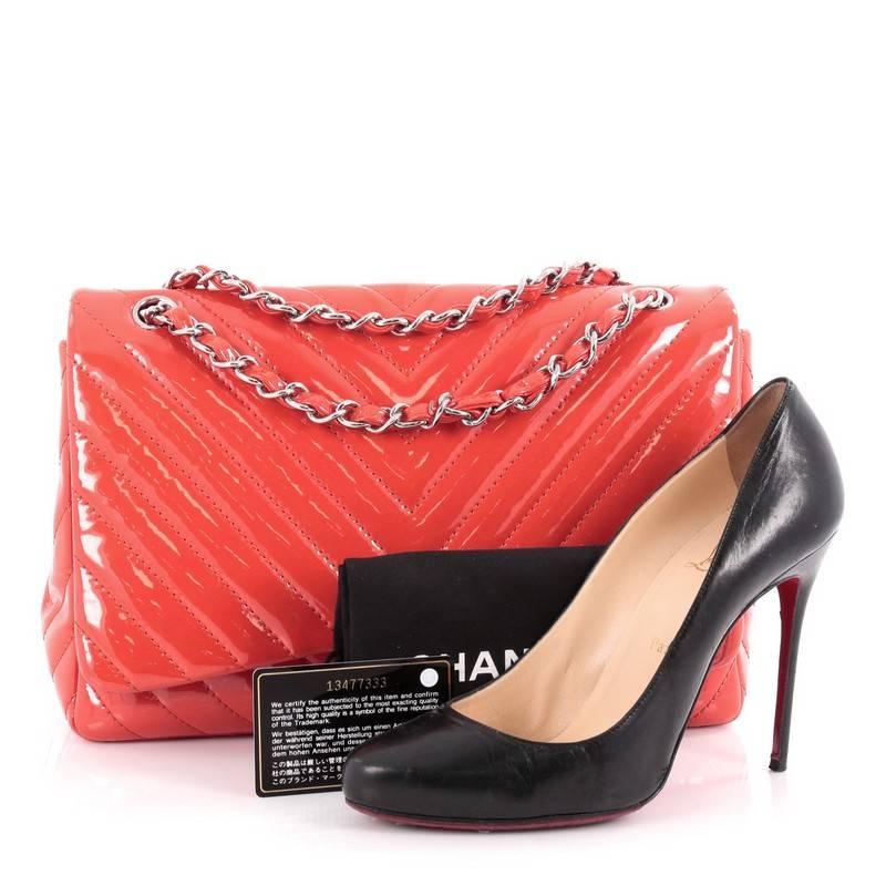 This authentic Chanel Classic Single Flap Bag Chevron Patent Jumbo is a timeless essential for any modern woman. Crafted in cinnabar red patent leather, this large classic flap features woven-in leather silver chain strap, Chanel's chevron quilting,