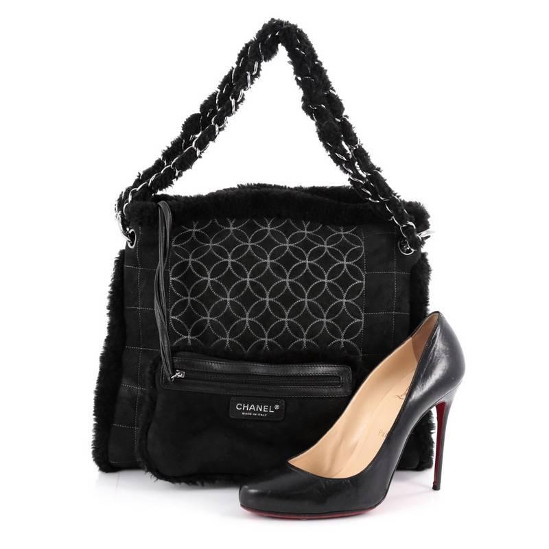 This authentic Chanel Embroidered CC Chain Tote Quilted Suede and Shearling is made for the colder season. Crafted from black quilted suede and shearling trims, this stylish tote features woven-in shearling chain straps, CC stitched logo and