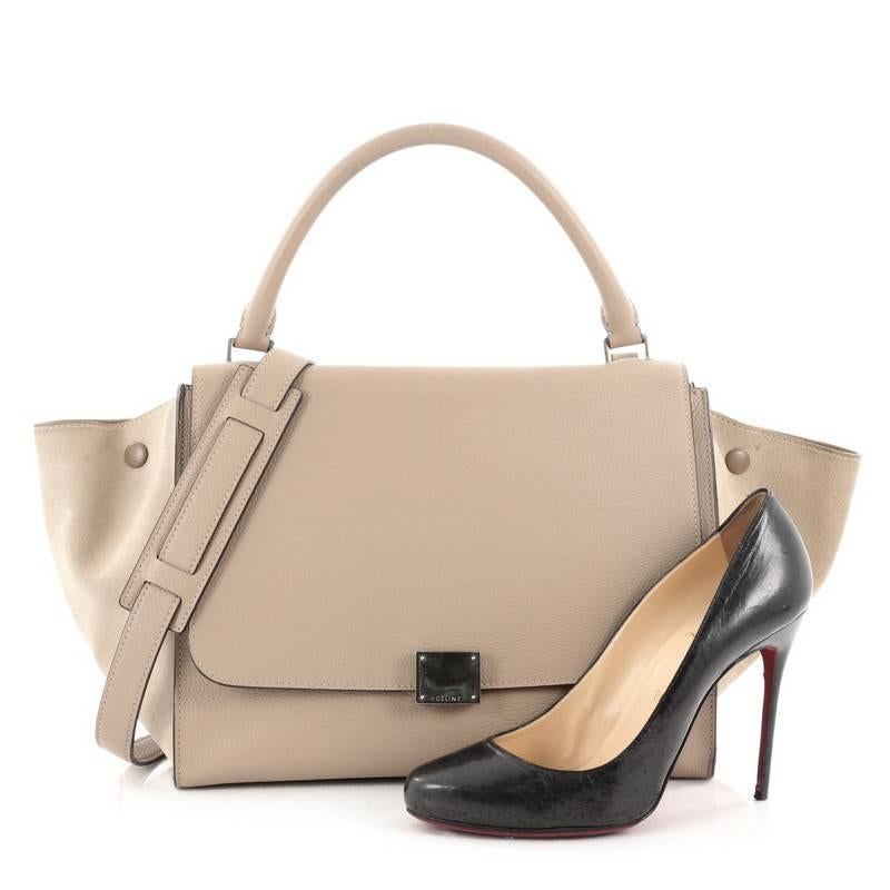 This authentic Celine Trapeze Handbag Leather Medium is a fashionista's dream. Crafted in light taupe leather with beige suede wings, this classic bag features silver-tone hardware accents, exterior back pocket and top handle with removable shoulder