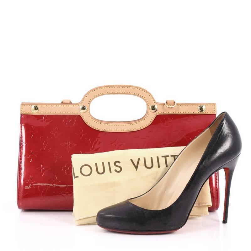 This authentic Louis Vuitton Roxbury Drive Handbag Monogram Vernis showcases a unique boxy, triangular silhouette. Constructed from red monogram vernis, this bag features flat vachetta leather handles and trims, stud detailing, and gold-tone