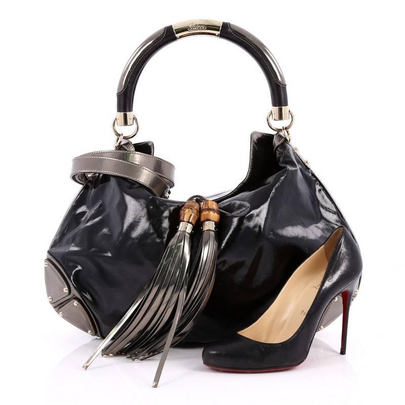 This authentic Gucci Indy Hobo Patent Large showcases the brand's classic design with luxurious detailing adding an industrial chic twist. Crafted from black patent leather, this eye-catching hobo features bamboo and fringe tassels, metallic leather