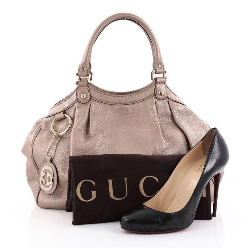 This authentic Gucci Sukey Tote Leather Medium is a chic tote ideal for your everyday wear. Crafted from light rose gold leather, this pleated tote with a ring charm accent features dual-rolled leather top handles, side snap buttons, and gold-tone